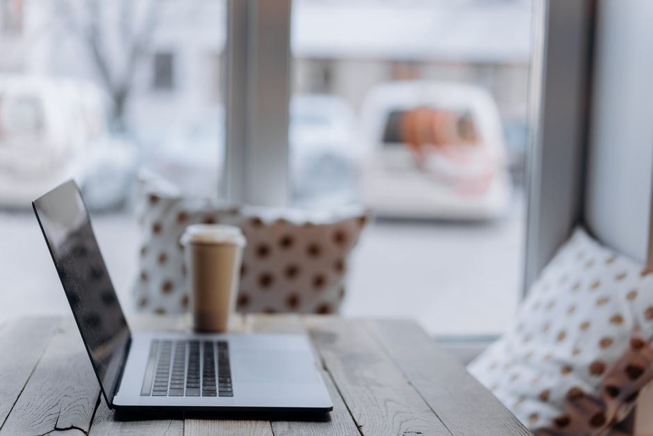 Cozy workspace with a laptop and coffee cup by a window, ideal for productivity.